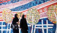 Two Iranian women walk along a street past a mosaic mural on Jaunary 14, 2017 (AFP / Atta Kenare) 