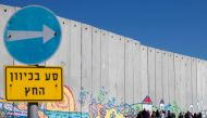 Israeli tourists take pictures of graffiti on part of Israeli controversial separation barrier in the Israeli Kibbutz of Netiv Haashara along the border between Israel and the Gaza Strip on February 7, 2017. AFP / Jack Guez