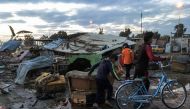A picture taken with a mobile phone on February 16, 2017 shows two Iraqi children walking with a bicycle at the scene of a blast by a massive car bomb which killed dozens in a used car market in southern Baghdad. The Amaq propaganda agency linked to the I