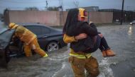 SUN VALLEY, CA:  A firefighter carries a woman from her car after it was caught in street flooding as a powerful storm moves across Southern California on February 17, 2017 in Sun Valley, California. David McNew/Getty Images/AFP