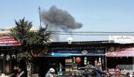 Palestinians drive on a road as smoke billows, in the background, following an Israeli airstrike on Rafah, in the southern Gaza Strip on February 27, 2017. / AFP / SAID KHATIB
