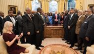 Counselor to the President Kellyanne Conway (L) checks her phone after taking a photo as US President Donald Trump and leaders of historically black universities and colleges pose for a group photo in the Oval Office of the White House before a meeting wi
