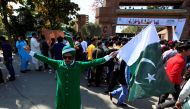 A Pakistani spectator holds a national flag as he waits for his turn to enter Gaddafi Cricket Stadium to watch a hugely anticipated finals of its domestic cricket league, Pakistan Super League (PSL) in Lahore, Pakistan, March 5, 2017. (REUTERS/Faisal Mahm
