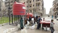 Syrians stand in queue next to a water reservoir in the once rebel-held Shaar neighbourhood in the Northern Syrian city of Aleppo on March 9, 2017. / AFP / JOSEPH EID
