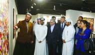 Iranian artist Siamak Azmi (left) explains one of his paintings to Katara General Manager Dr Khalid bin Ibrahim Al Sulaiti (third right) as other guests look on.