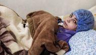 Dania, a 14-year-old Syrian who suffers from renal insufficiency, sits on a bed as she receives a dialysis session inside a basement-turned-clinic in the rebel-held town of Douma, on the outskirts of the capital Damascus, on March 16, 2017.  AFP / Sameer 