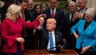 US President Donald Trump (C) gives a pen to US Congresswoman Liz Cheney, R-Wyoming, after signing H.J. Resolution 37, 44, 57 and 58 at the White House in Washington, DC, March 27, 2017. / AFP / JIM WATSON
