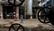 A worker walks past oil pipes at a refinery in Wuhan, Hubei province March 23, 2012. REUTERS/Stringer/File Photo.