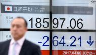 A businessman walks past a stock quotation board flashing the Nikkei 225 key index of the Tokyo Stock Exchange in front of a securities company in Tokyo on April 6, 2017. AFP / Toru YAMANAKA
