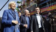 French presidential election candidate for the far-right Front National (FN) party Marine Le Pen (L) and FN Vice-President Florian Philippot (R) and the founder of the Foire du Trone, Marcel Campion, visit the fairgrounds in Paris on April 7, 2017. / AFP 