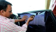 An employee at a car accessory shop installing tinted film on a car in Doha yesterday. Pic: Salim Matramkot / The Peninsula