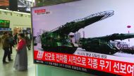 People walk past a television screen broadcasting live footage of a parade to mark the 105th anniversary of the birth of North Korea's founder Kim Il-Sung, at a railway station in Seoul on April 15, 2017.   AFP / JUNG Yeon-Je

