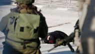 FILE PHOTO: A Palestinian woman lies on the ground after she was shot and wounded by Israeli security forces at Qalandia checkpoint between Jerusalem and the occupied West Bank on December 30, 2016 (AFP /  ABBAS MOMANI)
