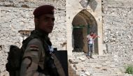 A member of the Iraqi security stands guard as Ameen Mukdad (R), a violinist from Mosul who lived under ISIS's rule for two and a half years where they destroyed his musical instruments, performs at Nabi Yunus shrine in eastern Mosul, Iraq, April 19, 2017