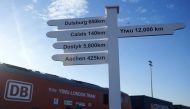 FILES- This file photo taken on January 18, 2017 shows a sign showing the distance in kilometers to various destinations as a freight train transporting containers laden with goods from China, arrives at DB Cargo's London Eurohub rail freight depot in Bar