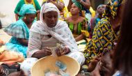 Binta Ndoye sits on a mat in a home in Grand-Mbao, on March 9, 2017, as she counts the money for a 