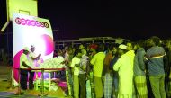 Representatives of Ooredoo distributing healthy snacks and food vouchers at a workers' camp. 
