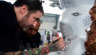 A tattoo artist draws at the 6th Edition of the Paradise Tattoo Convention in San Antonio de Belen, 20 km west of San Jose, Costa Rica on May 5, 2017, which drew more than 300 local and international tattoo artists. / AFP / EZEQUIEL BECERRA
