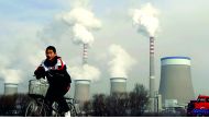 A Chinese boy cycles past a cooling towers of a coal-fired power plant in Dadong, Shanxi province, China, in this file photo.