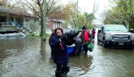 Mina Tayarani carrying a bag of her belongings as she is evacuated from her home in a flooded residential neighbourhood in Ile Bizard, Quebec, yesterday.