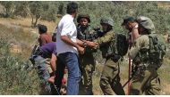 A Palestinian boy is being held by Israeli security forces for a while after a Palestinian agricultural land was set on fire by a group of Jewish settlers in Burin district of Nablus, West Bank on May 10, 2017. / AA.