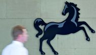 A man passing a Lloyds logo outside the entrance to an office of Lloyds Banking Group in London.