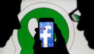 An illustration photo shows a man holding a smart phone with a Facebook logo as its screen wallpaper in front of a WhatsApp messenger logo February 20, 2014. REUTERS/Dado Ruvic /Illustration/File Photo