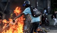  A hooded protester throws gas into the flames during a protest against the government of President Nicolas Maduro in Caracas on May 20, 2017. ( Carlos Becerra - Anadolu Agency )