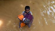A Sri Lankan boy carries pillows through floodwaters from his home in Kelaniya on May 27, 2017.  AFP / Ishara S. Kodikara
