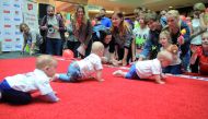 Babies take part in a Baby Race to mark International Children's Day in Vilnius, Lithuania, yesterday. Parents and grandparents waved colourful toys, mobile, phones, balloons, TV remote controls, plastic bottles and even bagels to get their tots across th