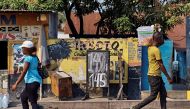 People walk in front of a store that advertises an exchange rate in Kinshasa, Democratic Republic of the Congo June 9, 2017. Picture taken June 9, 2017. (REUTERS/Robert Carrubba)