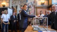 French President Emmanuel Macron (C) casts his ballot next to his wife Brigitte Macron (L) at a polling station during the first round of the French legislative elections in Le Touquet, on June 11, 2017. / AFP.