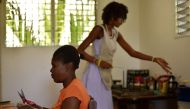 Magoina (L) and Daniella (R) work producing soap at the Anacaona company in Port-au-Prince on June 6, 2017. AFP / HECTOR RETAMAL 
