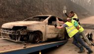 A burned car is moved onto a towing truck during a forest fire near Pedrogao Grande, Portugal June 18, 2017. REUTERS/Guillermo Martinez
