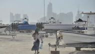 Man covering his face from the dust while walking through wave of  dusty winds at Doha corniche harbor Yesterday.  Baher Amin © The Peninsula