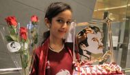 A Qatari girl holds flowers and pictures of HH the Emir Sheikh Tamim Bin Hamad Al-Thani at Hamad international airport in Doha, Qatar June 22, 2017. Reuters/Naseem Zeitoon