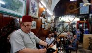Ahmad al-Lahham, a Syrian storyteller, reads from his storybook in a Damascus coffeehouse on June 19, 2017. AFP / LOUAI BESHARA
