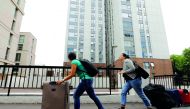 People with suitcases leave Taplow Tower residential block on the Chalcots Estate in north London, yesterday, as residents evacuate because of fire safety concerns.  