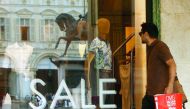 A pedestrian walks by a shop window displaying sales notices in Turin yesterday, as Italian retailers started their summer sales.