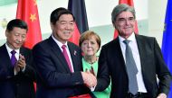 German Chancellor Angela Merkel (centre) and China's President Xi Jinping (left) look on as Siemens chairman Joe Kaeser (right) shakes hands with a Chinese business partner during a signing ceremony of German-Chinese business contracts at the Chancellery 