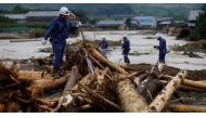 Police officers walk on woody debris which were swept by heavy rain as they conduct rescue and search operation in Asakura, Fukuoka Prefecture, Japan July 8, 2017. REUTERS/Issei Kato.