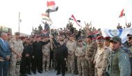 Iraqi Prime Minister Haider al-Abadi (C) holds an Iraqi flag as he announces victory over Islamic State in Mosul, Iraq, July 10, 2017. Iraqi Prime Minister Media Office/Handout via REUTERS.