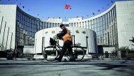 A man pushes a bicycle past the People's Bank of China headquarters in Beijing.