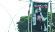A worker cleans a garden under a billboard with the portrait of Pakistani Prime Minister Nawaz Sharif along a street, in Islamabad, yesterday.