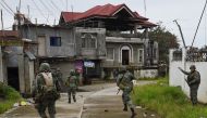 This photo taken on July 22, 2017 shows Philippine Marines taking cover from sniper fire while on patrol at the frontline in Marawi on the southern island of Mindanao, as fighting between government troops and Islamist militants enters its second month. A