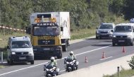 A refrigerated truck involved in similar incident is towed and escorted by police along a highway near Neusiedl am See, Austria, on 27 August 2015 (AFP)