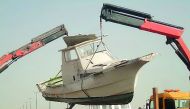 An abandoned motorboat is being removed from a port.