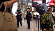 Police walk past passengers as they patrol Sydney Airport on July 30, 2017. (AFP / WILLIAM WEST)