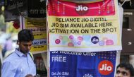 A pedestrian using a mobile phone walks past banners for Reliance Jio, the mobile network of Reliance Industries Ltd., and Bharti Airtel Ltd. outside a mobile phone store in Mumbai, India, on Oct. 24, 2016.(Bloomberg photo by Dhiraj Singh)