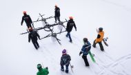 This January 14, 2017 photo shows snowboarders walking as sixteen propeller drone is carried to Niniera lake surface near Cesis, Latvia (AFP / Ilmars Znotins) 
